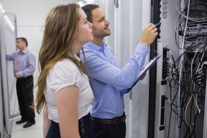 Technicians doing maintenance on servers with a clipboard